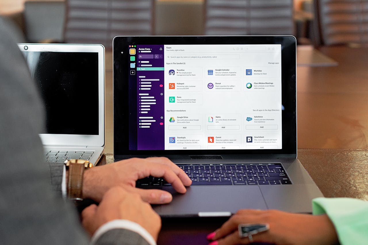 Two professionals collaborating using laptops and communication software in a business setting.
